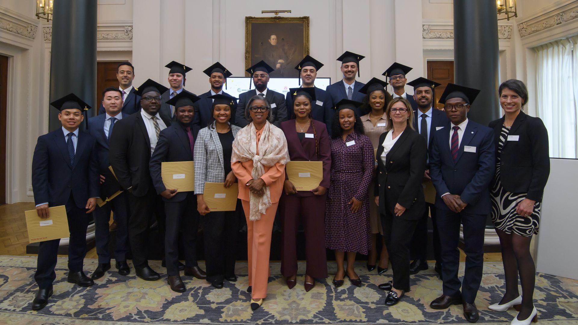 Large group of formally dressed students posing together in an elegant indoor venue with marble columns